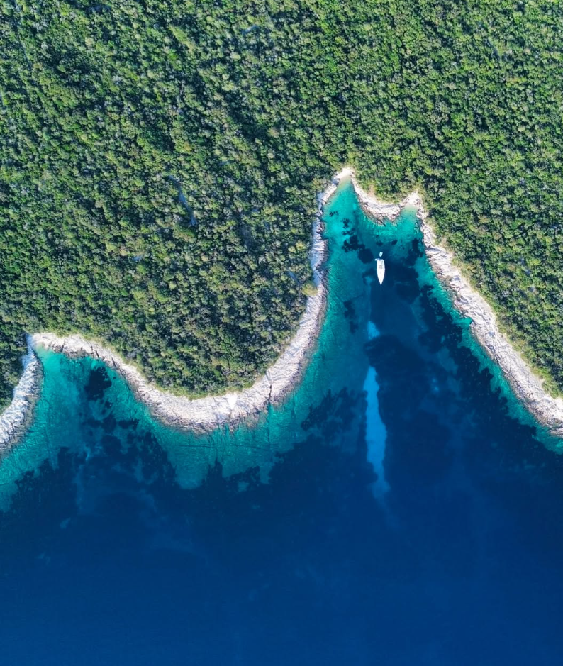 Segelboot in einer türkisen Bucht von oben